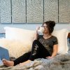 A woman wearing graphic bra free tee shirt enjoying coffee while doing work on laptop